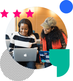 Two women on laptops discussing work